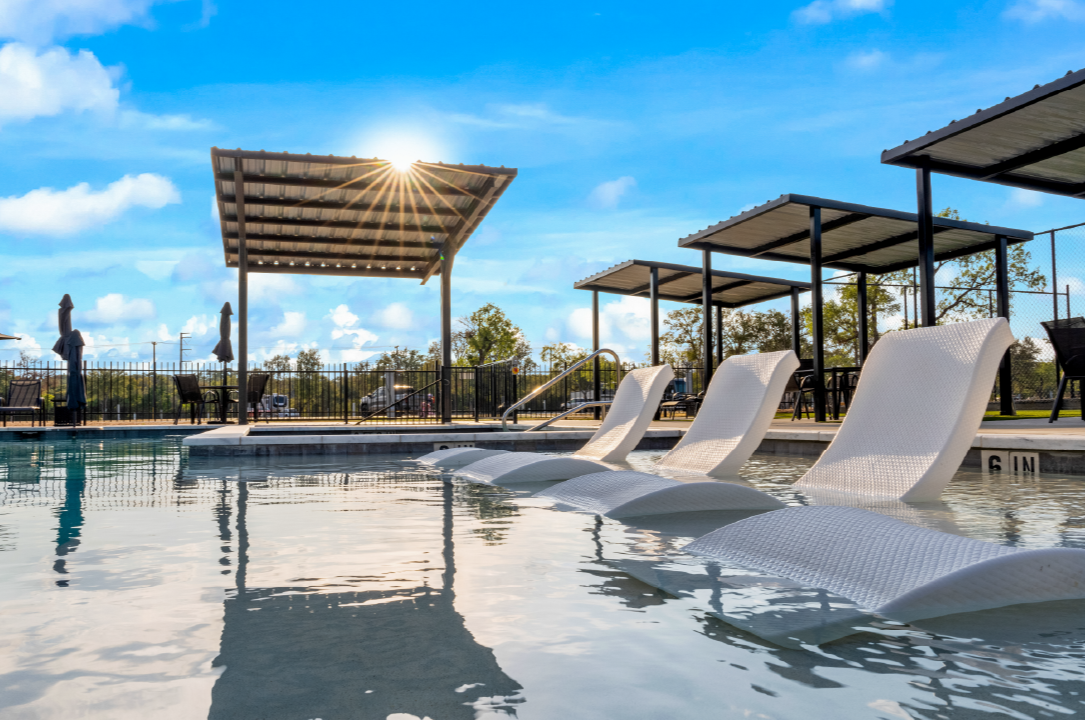 GAP-Ep29-Northgate Resorts-3rd Party Mgmt A luxurious outdoor resort pool featuring in-water lounge chairs under clear blue skies, with modern shaded cabanas and seating areas in the background. Sunlight shines through a slatted canopy, creating a warm, inviting atmosphere ideal for relaxation.