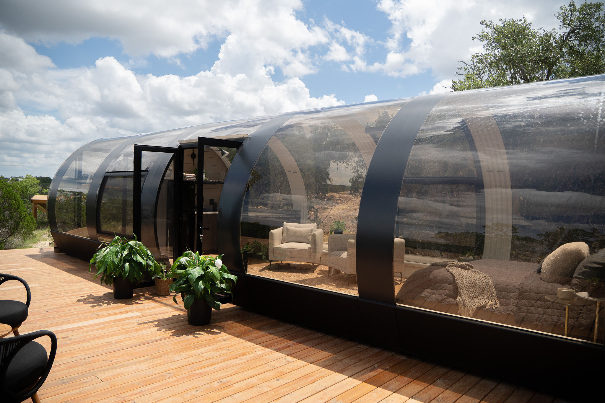 Alt text: Panoramic glass accommodation at Lagom Retreat designed for immersive nature views and dark-sky stargazing, featuring a transparent curved structure and spacious outdoor deck.