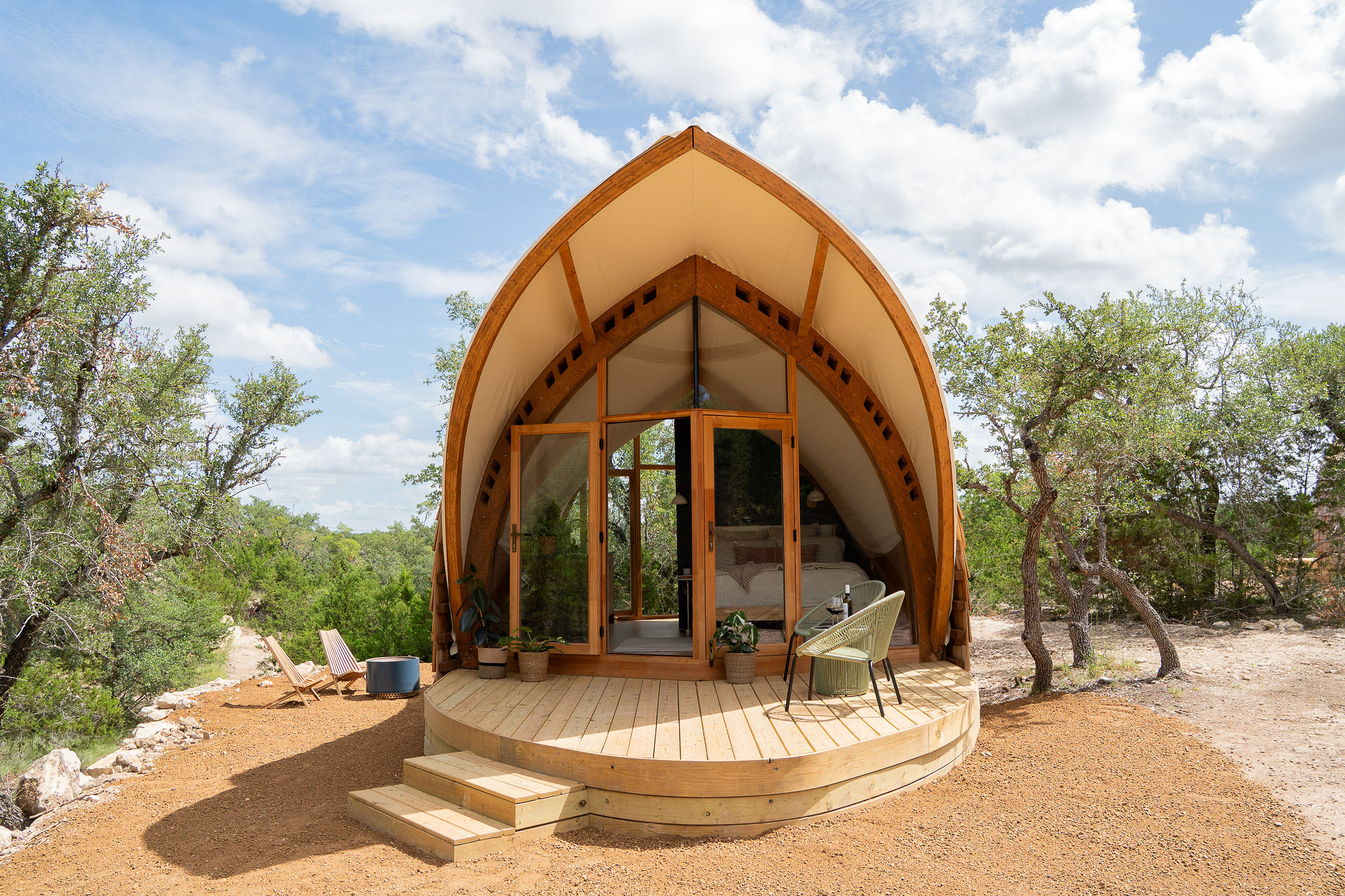 Unique arched glamping cabin at Lagom Retreat with floor-to-ceiling glass, warm wood construction and a private deck nestled among Texas Hill Country trees.